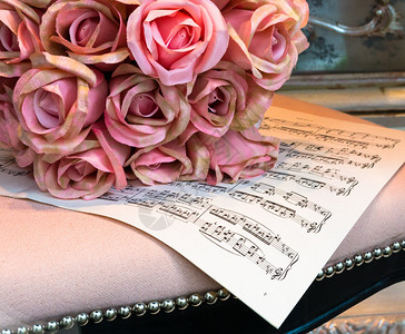 一束丝绸玫瑰在乐谱上图片