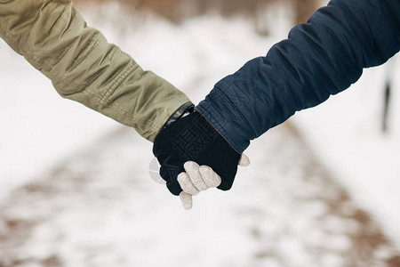 身着冬衣和手套手握在雪地公园的年轻夫图片