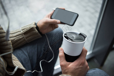 男子用咖啡和智能手机拿热水图片