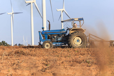 农夫在拖拉机上为有风力涡轮机发电的图片