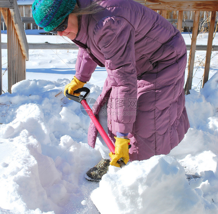 女从她的露台甲板上铲雪图片