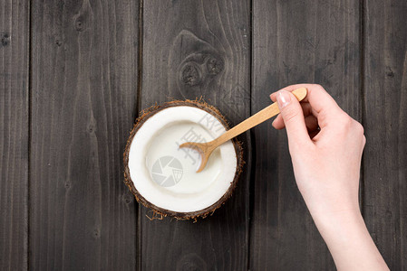 人手用木勺在椰子中混合牛奶椰奶图片