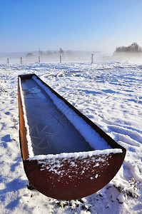 装满水的槽被放置在雾雪季节的冰冻景观中图片