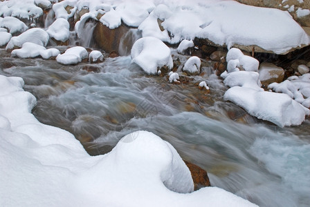在降雪期间的冬天山小河图片