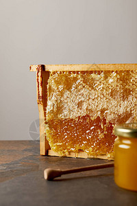 用蜂蜜蜂蜡和木蜂蜜在灰色背景下更深的玻璃罐的特写视图图片