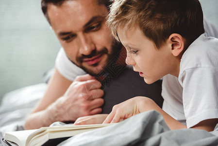 父亲和儿子在床上阅读背景图片