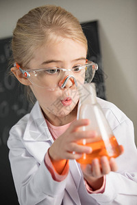 身着实验室大衣和防护眼镜拿着橙色试剂的酒图片