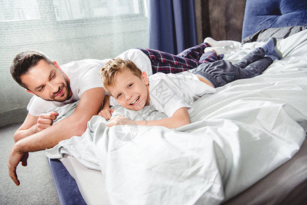 快乐的父亲和儿子躺在床上图片