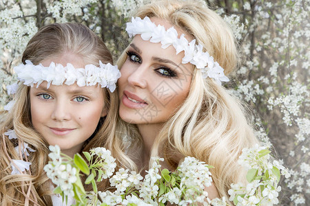 美丽的年轻母亲及其女儿穿着春衣和花圈图片