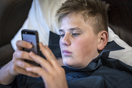 年轻少年男孩在他的手机上读短信图片