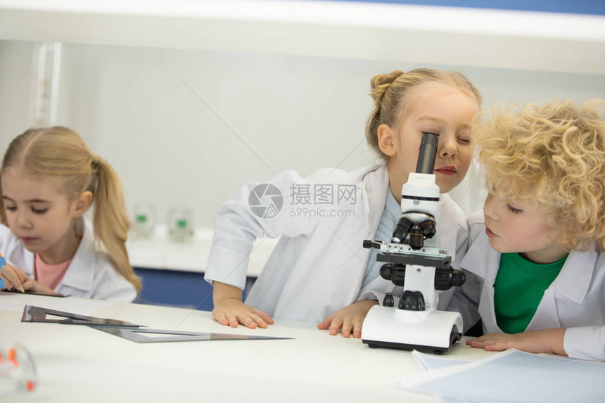 小孩子在科学课上用显微镜看图片