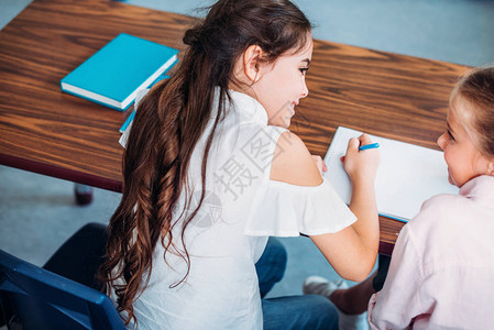 女孩坐在学校办公桌边聊天图片