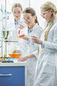 三名微笑的年轻女科学家在化工实验室做实验图片