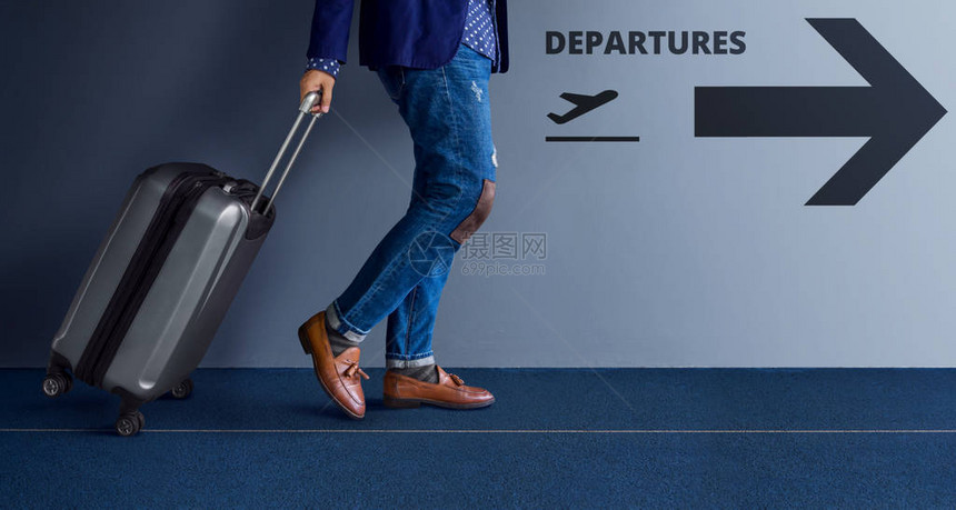 旅行概念年轻旅行者随手提箱行走和在机场遵循离境标志图片