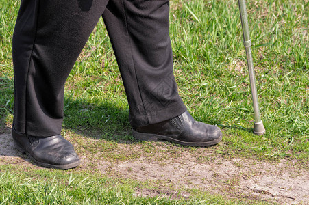 穿着旧的刮伤鞋在泥土路上行走的男人图片