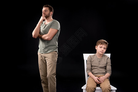 父亲手站在下巴上男孩坐在凳子上心烦意乱的图片