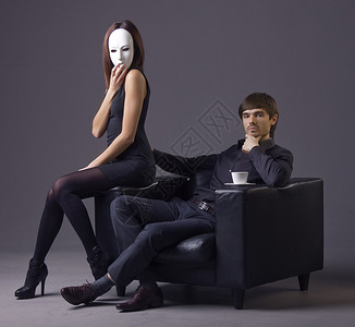 傲慢的男人和戴面具的妇女坐在椅子上图片