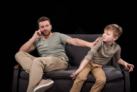 胡子人谈论智能手机和推小儿子坐在沙发上图片