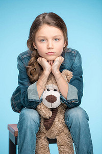 心烦意乱的小女孩抱着泰迪熊被蓝色隔离的肖像图片
