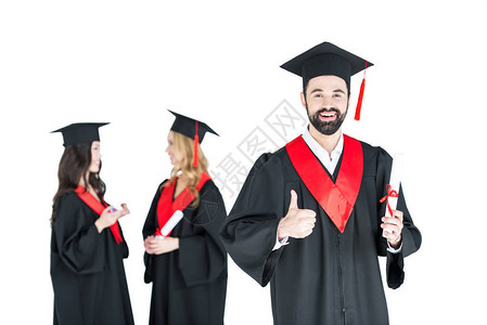 快乐的青年男子在学术帽子持有文凭和显示拇指图片