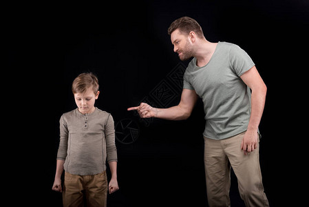 愤怒的父亲威胁和示意害怕的小儿子家图片