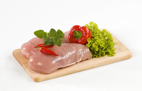 切菜板上的生鸡胸肉和蔬菜图片