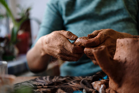 在陶器工作场所用粘土的人手波特在工作用火泥块紧靠少爷的手陶器粘土图片