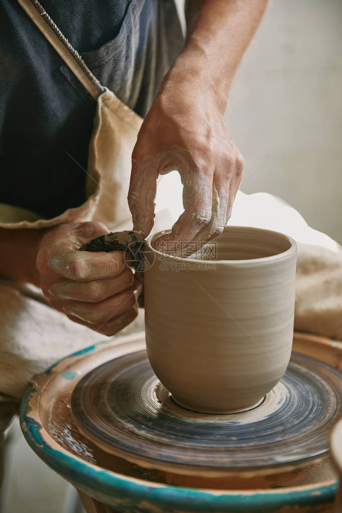 在陶瓷工作室的陶器车轮上工作的男手工艺图片