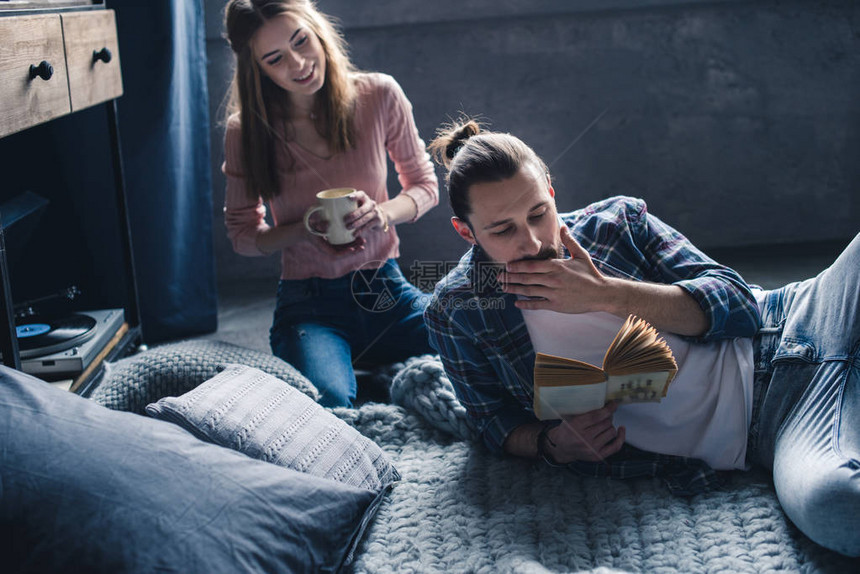 年轻夫妇在家喝咖啡时一起看书同时图片
