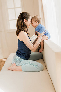 母亲和婴儿男孩坐在沙发上当着家庭面对图片
