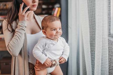 以可爱的婴儿男孩站在窗边图片