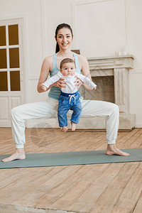 母亲带着孩子站在瑜伽台上在家图片