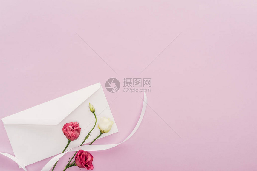 花朵和信封的顶部视图在粉红色上与图片