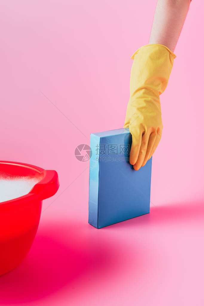 戴橡胶手套的妇女在塑料盆附近用粉红色背景泡沫喷发洗图片