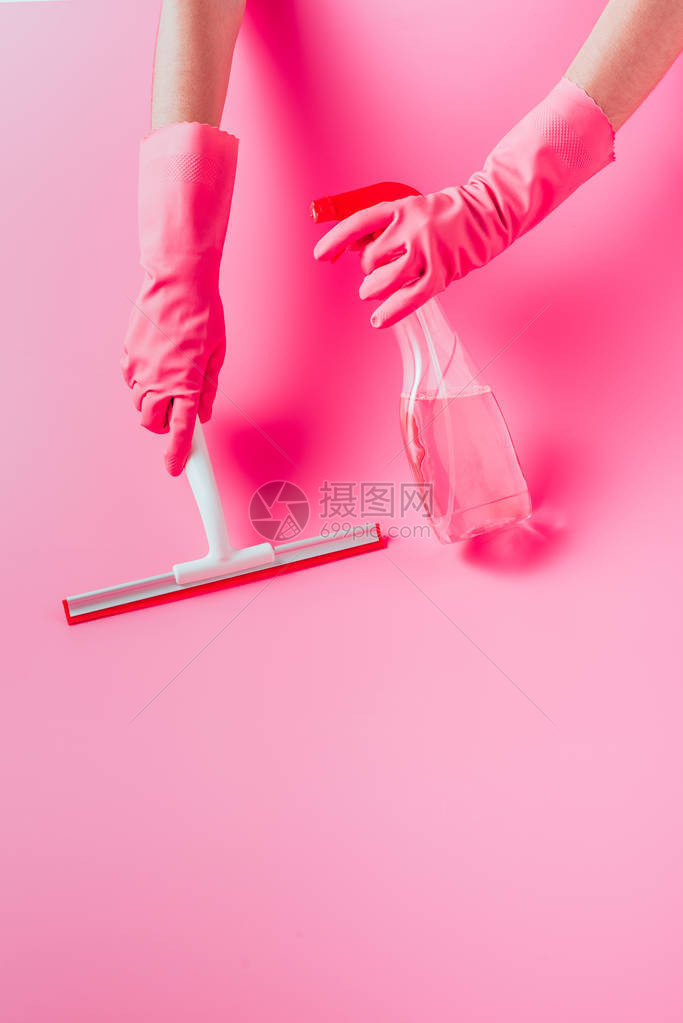 用清洁液粉红色背景的刮刀在橡胶手套清洁地板中裁剪女图片