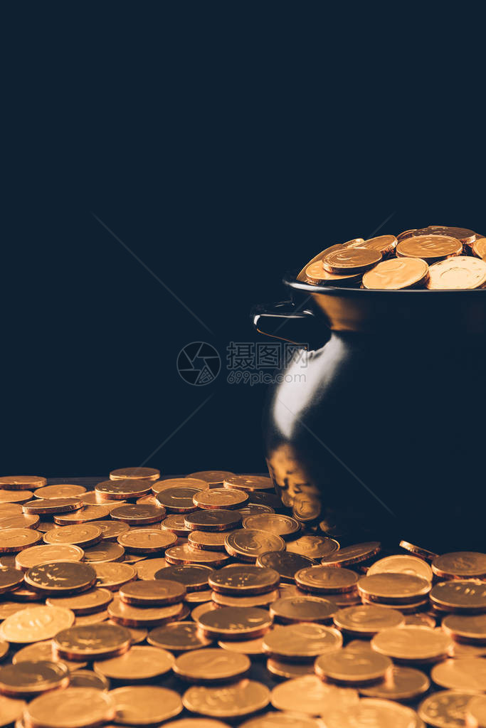 黑色锅有闪亮的金币孤立在黑色图片