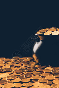黑色锅有闪亮的金币孤立在黑色背景图片