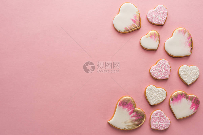 与粉色表面隔离的冰红心形饼干图片