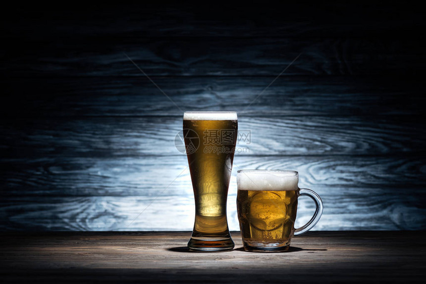 在木制桌上的杯子上装着不同杯子的啤酒图片