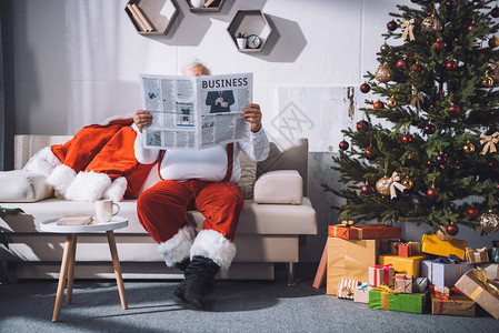 坐在沙发上阅读商业报纸的难看的Santa图片