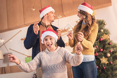 喜悦的家庭在圣塔的帽子里与家里有圣诞树的图片