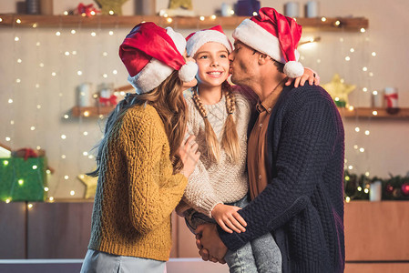 圣诞时亲吻笑女儿的喜悦之情圣塔帽图片