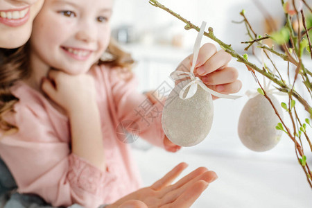 快乐的孩子有选择焦点抚摸着装饰好的东方鸡蛋在柳树枝上图片