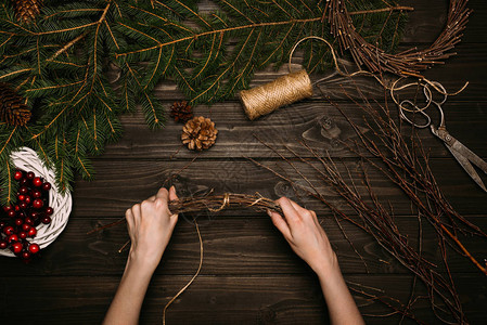 花匠双手在木板上的树枝上制作圣诞花图片
