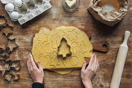 女手生面粉圣诞节饼干面包和木板上的饼干切割机的原料以图片
