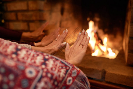 夫妇在家里的壁炉旁暖手图片