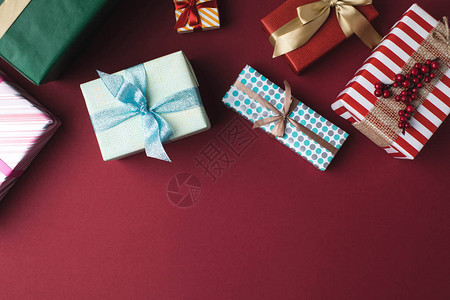 红色桌面上带丝的包着圣诞礼物箱图片
