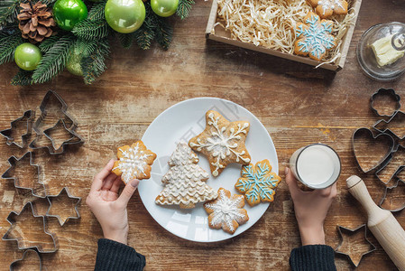 妇女将牛奶和饼干的杯子放在装饰圣诞节花环和纸板盒的木桌顶图片