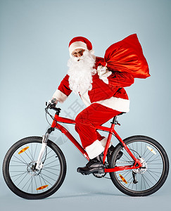 圣诞老人在骑自行车时拿着图片