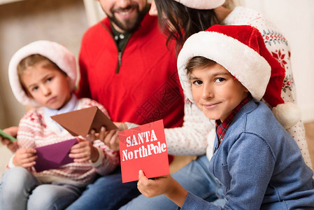有两个孩子拿着信封的圣诞老人的信袋的家庭图片